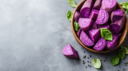 Vibrant Purple Sweet Potato Chunks in Rustic Bowl with Fresh Green Basil Leaves and Peppercorns