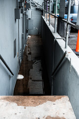 Grungy outdoor stairwell with puddles reflecting the brick wall and utility boxes © Tom