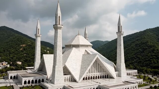 White mosque with four slender minarets atop a hill, surrounded by green mountains and clouds above!