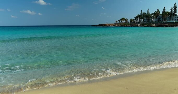 Ground level view of clear turquoise sea with gentle waves at sandy beach in Protaras
