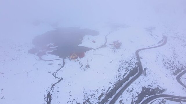 Aerial view at Balea lake in Romania, in winter season. Video was shot from a drone while lowering altitude through the fog with the lake in the view.