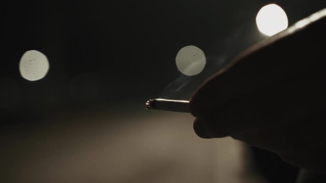 Man holding a burning cigarette at night