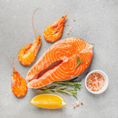 Omega rich seafood ingredients with fresh salmon steak and shrimp on stone background arranged flat lay, top view