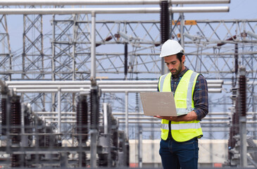Professional engineer using a laptop with futuristic digital data overlays to inspect equipment at a high-voltage electrical power substation.