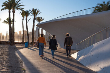 Tourists strolling backlit along the Paseo Mar&iacute;timo de Poniente, Benidorm