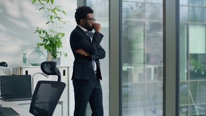 African American business man businessman male guy worker in office near window with hand on glass feeling stressed thoughtful corporate suffering from anxiety pressure thinking worried work lost