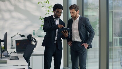 Two diversity businessmen talking in office using modern digital tablet together talk multiethnic business men male co-workers discussing online internet corporate result startup development partners