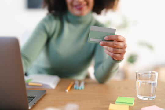 A person holds a credit card while using a laptop, ready to make an online purchase.
