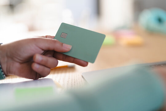 A person holds a payment card, ready to make a transaction. The card features a chip and a network logo.