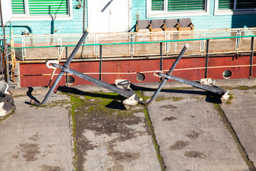 Two old ship anchors on a sunny pier