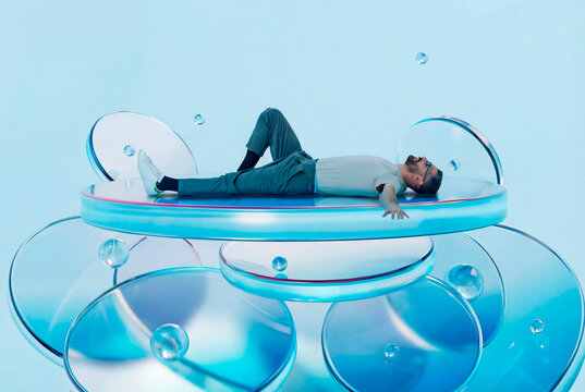 Man laying on 3D discs with floating glass textures