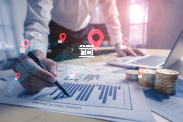 A business professional analyzes financial reports with digital location markers, highlighting data visualization in a modern workspace for strategic decision-making. Gantry