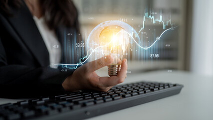 A business professional holds a glowing light bulb, representing innovation. Digital charts and data surround them, reflecting analytical growth in a modern office setting. Scalp
