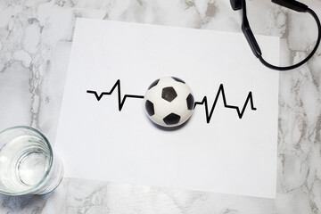 Soccer ball on a drawn electrocardiogram line representing the emotional impact of sports