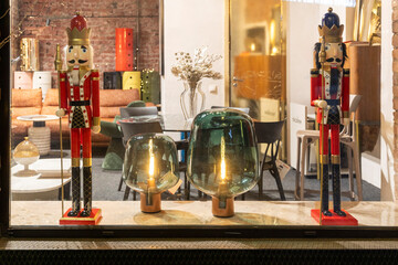 Moscow, Russia, ARTPLAY Design and Architecture Center. Shop window displaying two tall red nutcracker soldiers flanking green glass lamps and modern furniture on a reflective floor, visible. 