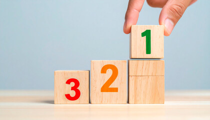 Hand placing a wooden block labeled &ldquo;1&rdquo; atop two stacked blocks labeled &ldquo;2&rdquo; and &ldquo;3&rdquo; featuring a podium. The image symbolizes prioritization, competitiveness, achieving budgets in the business world.