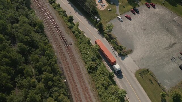 Drone Footage Captures A Semi Truck Carrying A Shipping Container Departing PSA Halifax Fairview Cove In Nova Scotia Canada Surrounded By Port Cranes And Cargo Areas On A Clear Bright Day