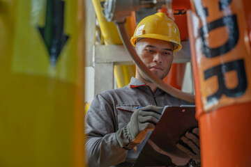 Asian engineer wearing glasses working in the boiler room,maintenance checking technical data of...