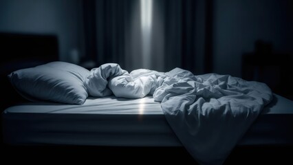 Unmade bed with crumpled white sheets and a pillow in a dark bedroom at night. Concept of insomnia, rest, or waking up.