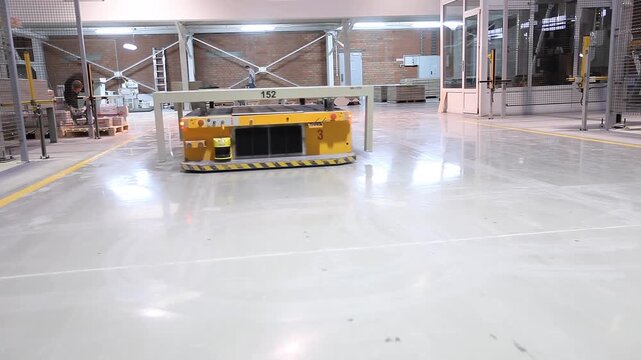Smart factory inside. Autonomous guided vehicles and Autonomous Mobile Platform transport products in a large manufacturing plant, indoor. Factory for the production of ceramic tiles.