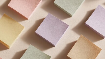 Group of small, square-shaped objects arranged in a scattered manner on a light pink background.
