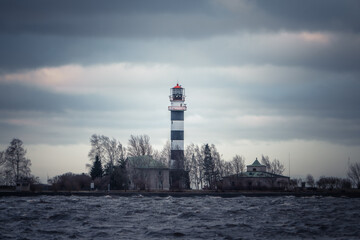 Lighthouse tower standing by a coastal waterway under dramatic skies