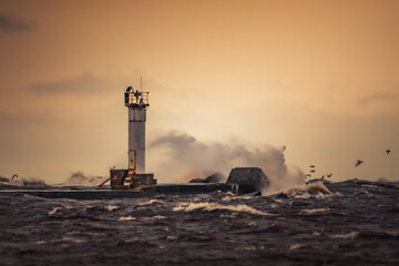 Lighthouse Standing Strong Amidst Rough Seas at Sunset
