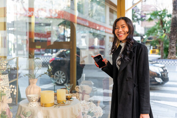 Latina asian businesswoman smiling holding smartphone in city