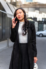 Latina businesswoman talking on smartphone in city street