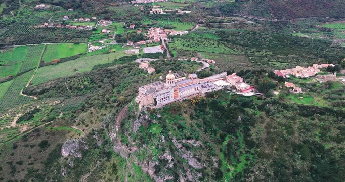 Aerial view of the Sanctuary of Tindari perched atop a rocky cliff, offering a striking contrast against the lush greenery, Tindari, Sicily, Italy.