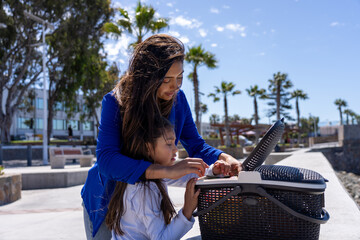 Mother and daughter preparing a picnic basket during family outing under palm trees
