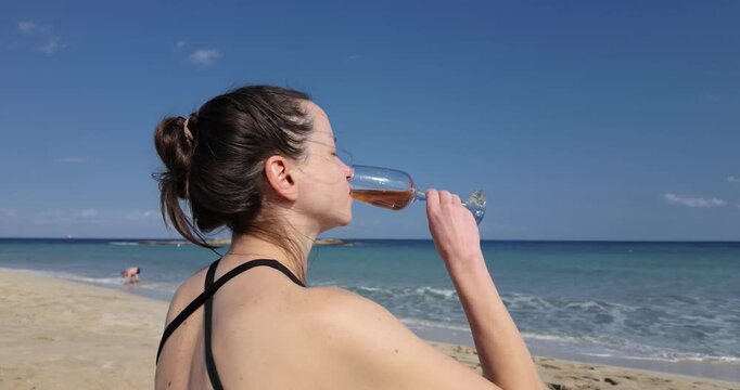Woman Drinking Rose Wine on Beach in Slow Motion and Looking at Sea
