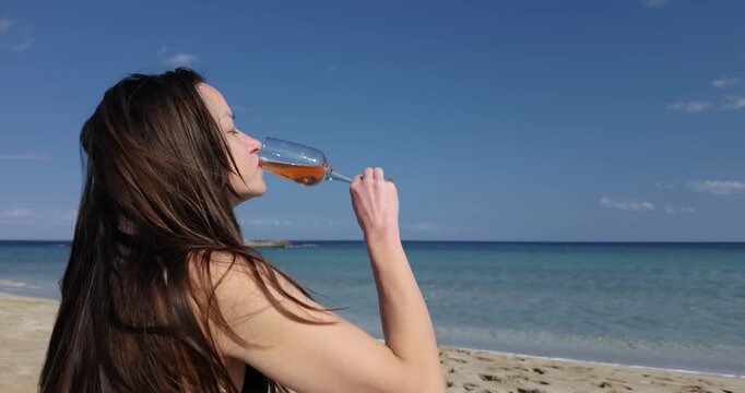 Woman Drinking Rose Wine on Beach in Slow Motion with Loose Hair