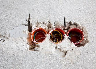 Three red electrical sockets installed in the brick wall