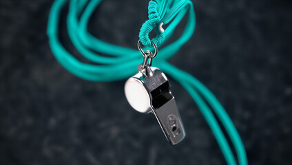 Metal whistle with blue cord isolated on black background