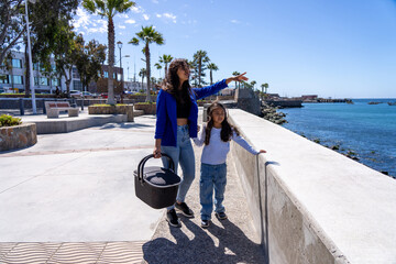 Mother pointing out to sea while daughter holding hands
