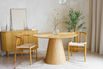 Minimalist dining space with round wooden table, bouquet of dried flowers, chairs and natural textures. Bright modern interior with neutral tones, plants and soft dayligh, Scandinavian home atmosphere © katyamaximenko