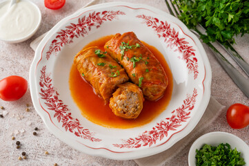 Cabbage rolls with meat, rice, vegetables and tomato sauce in a plate on a concrete background. Ukrainian cuisine.
