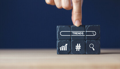 Hand pressing button with trends symbol on black stone block on wooden table top