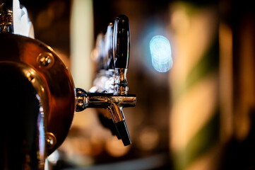 A close-up shot of shiny, metal beer taps with black handles on a bar counter, ready for pouring...