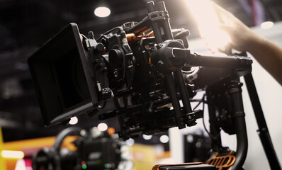 Behind the scenes of movie shooting or filming or video production with high quality camera and tripod equipment set up and professional film crew team in studio lighting. Video production camera gear