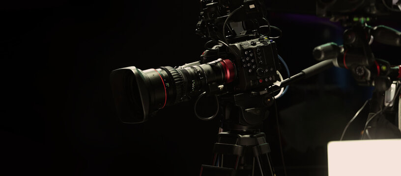 Behind the scenes of movie shooting or filming or video production with high quality camera and tripod equipment set up and professional film crew team in studio lighting. Video production camera gear