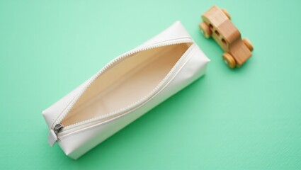 Minimalist open pencil case and wooden toy car on green background
