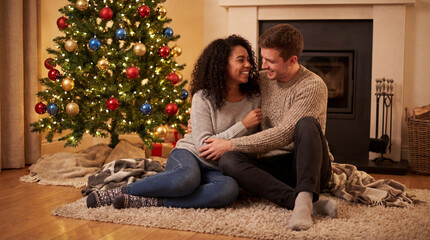 Obraz premium Couple hugging in front of decorated Christmas tree