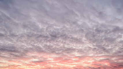 Dramatic sunset sky with textured clouds glowing in pink and orange colors during evening twilight
