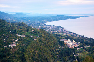 Aerial view captures Abkhazian coastal city at pink sunset where urban layout meets Black Sea horizon.