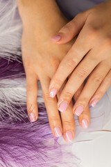 Fototapeta premium Close up of professional manicure process. Nail technician wearing gloves holding female hands with pink gel polish in beauty salon. Nail care, hygiene, spa treatment concept.