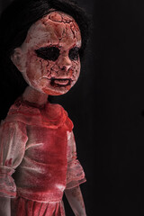 Creepy bloody doll face with long black hair in the dark