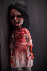 Creepy bloody doll face with long black hair in the dark