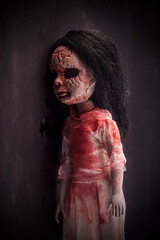 Creepy bloody doll face with long black hair in the dark